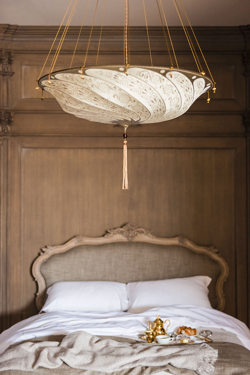 Lámpara Fortuny Scudo Saraceno Serpentine de seda marfil en habitación de hotel
